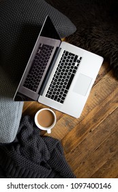 Clean, Modern Laptop On Dark Rustic Wood With Cushions, Blanket, Mug Of Coffee And Sheepskin Rug. Brown, Black, White. Semi Flat Lay/overhead Shot. 