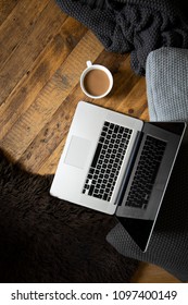 Clean, Modern Laptop On Dark Rustic Wood With Cushions, Blanket, Mug Of Coffee And Sheepskin Rug. Brown, Black, White. Semi Flat Lay/overhead Shot. 