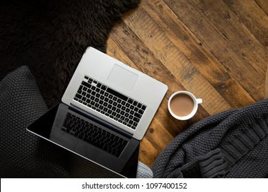 Clean, Modern Laptop On Dark Rustic Wood With Cushions, Blanket, Mug Of Coffee And Sheepskin Rug. Brown, Black, White. Semi Flat Lay/overhead Shot. 