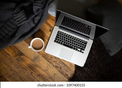 Clean, Modern Laptop On Dark Rustic Wood With Cushions, Blanket, Mug Of Coffee And Sheepskin Rug. Brown, Black, White. Semi Flat Lay/overhead Shot. 