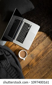 Clean, Modern Laptop On Dark Rustic Wood With Cushions, Blanket, Mug Of Coffee And Sheepskin Rug. Brown, Black, White. Semi Flat Lay/overhead Shot. 