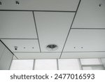 A clean, modern office ceiling featuring air vents, recessed lighting, and a grid pattern.