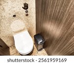 A clean and modern restroom features a white toilet with touchless controls and a waste bin, highlighting contemporary design elements.