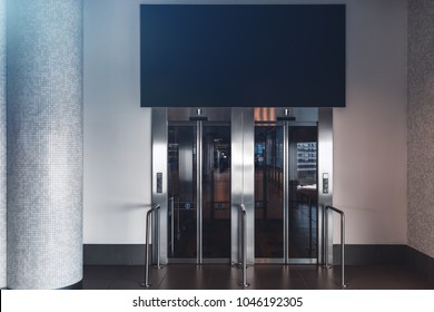 Clean and neat double elevator in a modern airport terminal or a railway depot station with empty blue banner mock-up above; paired lift in a shopping mall with the template of the banner over it