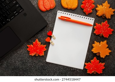 a clean notebook for notes next to a laptop and orange cookies