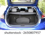 Clean, open empty trunk in blue car close up. Empty trunk of a modern blue car. Car boot is open. Modern electric car with open empty trunk. Open luggage carrier of vehicle close up.
