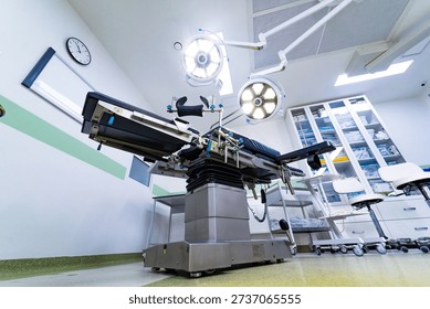 Clean operating room with surgery table and supply cabinet. General view of a sterile medical room with professional equipment and glass cabinets for supplies.