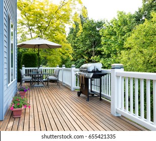 Clean Outdoor Cedar Wooden Deck And Patio Of Home With BBQ Cooker And Bottled Beer  