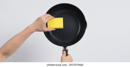 Clean the pan, Man in grey color T shirt cleaning the non stick pan with handy dish washing sponge which yellow color on the soft side and green on hard side for hygiene after cook. white background.
 - Powered by Shutterstock