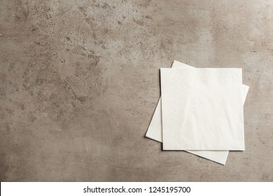 Clean paper napkins and space for text on grey background, top view