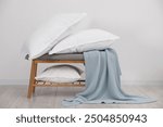 Clean pillows, blanket and storage bench on floor near white wall