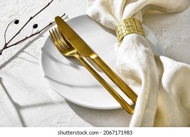 Clean plate with napkin and cutlery on white table