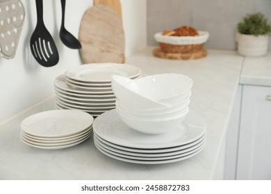 Clean plates and bowls on white marble countertop in kitchen - Powered by Shutterstock