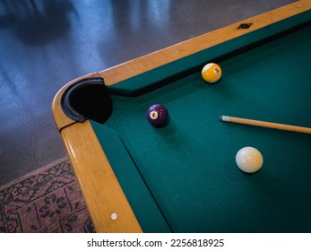 Clean pool table with a few cue balls, 4 ball, 9 ball, and pool cue stick scattered on the table in a modern game room, medium horizontal shot