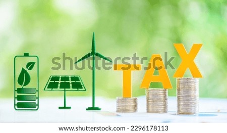 Clean, renewable energy or electricity production tax credits and incentives, financial concept : Green energy symbols e.g solar panel, wind turbine, fuel cell battery and the word TAX atop con stack.