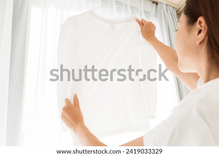 A clean routine of stretching and drying a plain white T-shirt.