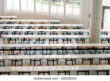 Clean School Cafeteria With Many Empty Seats And Tables.