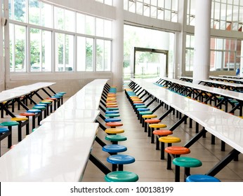 Clean School Cafeteria With Many Empty Seats And Tables.