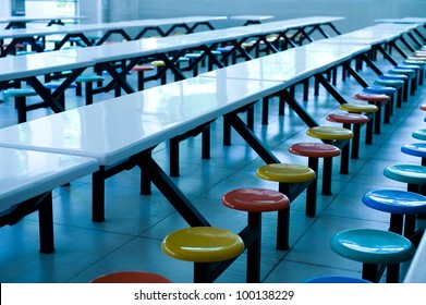 Clean School Cafeteria With Many Empty Seats And Tables.