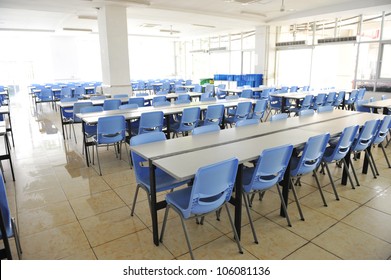 Clean School Cafeteria With Many Empty Seats And Tables.