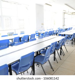 Clean School Cafeteria With Many Empty Seats And Tables.