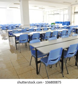 Clean School Cafeteria With Many Empty Seats And Tables.