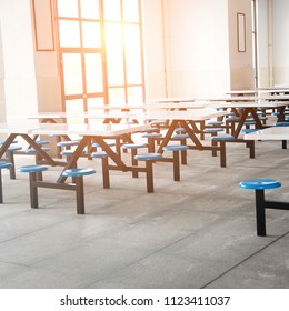 Clean School Cafeteria With Many Empty Seats And Tables.