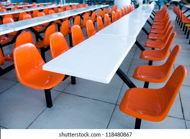 Clean School Cafeteria With Many Empty Seats And Tables.