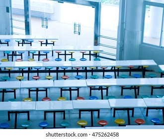 Clean School Cafeteria With Many Empty Seats And Tables.