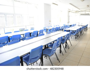 Clean School Cafeteria With Many Empty Seats And Tables. 