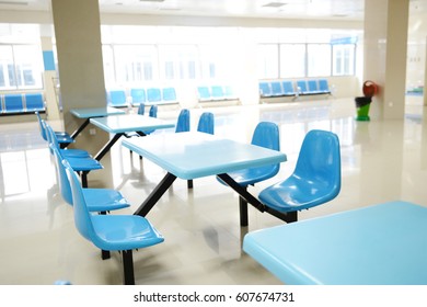 Clean School Cafeteria With Many Empty Seats And Tables.