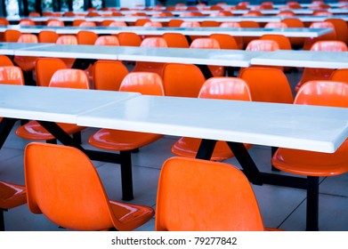 Clean School Cafeteria With Many Empty Seats And Tables.