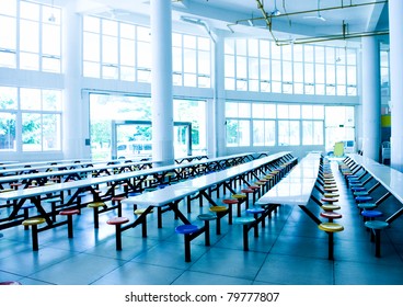 Clean School Cafeteria With Many Empty Seats And Tables.