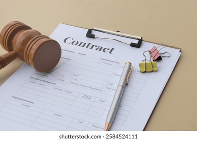 A clean and simple image of a contract paper in a clipboard set with a judge's hammer and pen on the table, perfect for legal presentations, educational materials, or contractual designs.