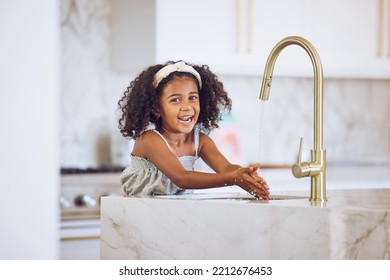 Clean, Smile And African Child Washing Hands With Water By The Tap In The Kitchen In A House. Happy Portrait Of A Girl Kid Cleaning Her Hand With Liquid For Health And Safety From Virus In Her Home