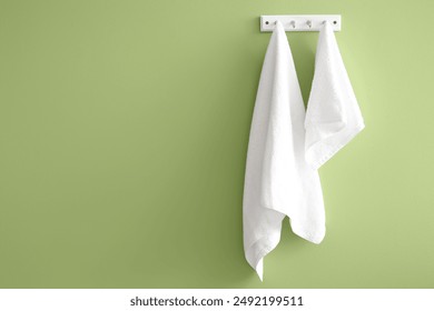 Clean soft towels hanging on green wall - Powered by Shutterstock