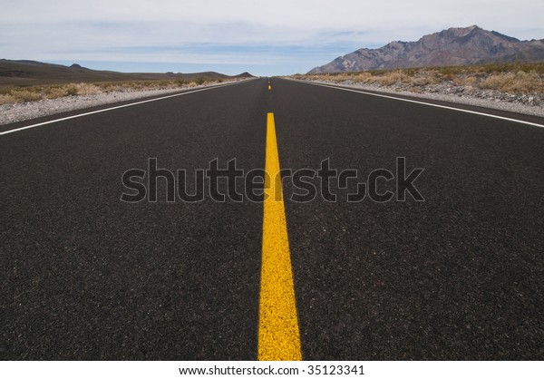 clean straight road through desert vanishing\
into distance