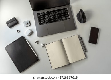 Clean top view desk setup featuring open bullet point notebook, smart ring wearable, ergonomic mouse, laptop, tablet, and phone. Minimalist digital workspace.