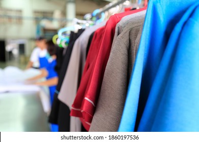 Clean uniforms are hanging on clothes line ready for delivery. Off focus staffs are over the background. Shot taken in the factory.