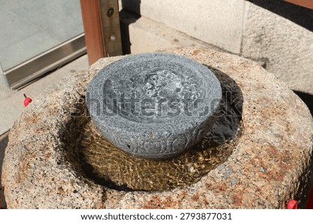 Clean water bubbles up and overflows from a circular stone basin stacked on a larger rock pedestal.