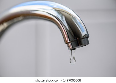 Clean Water Drop Falling From A Dripping Kitchen Faucet, An Unnecessary Waste Of Water In A World Threatened By Water Scarcity.