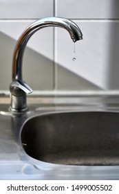 Clean Water Drops Falling From A Dripping Kitchen Faucet, An Unnecessary Waste Of Water In A World Threatened By Water Scarcity.