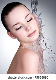 Clean water falling on the beautiful face of woman - studio shot
