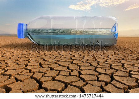 Clean water in plastic bottle on dry land of crakced earth metaphor save water, water crisis and Climate change impact to demand of water