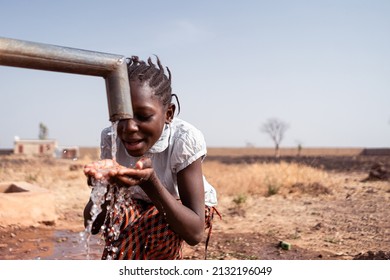 Clean Water Supply Concept: Young Black African Native Girl Drinking Healthy Fresh Water From A Village Tap