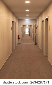 Clean and well-lit corridor features multiple doors along each side, creating a visually appealing perspective. The light at the far end invites exploration and curiosity