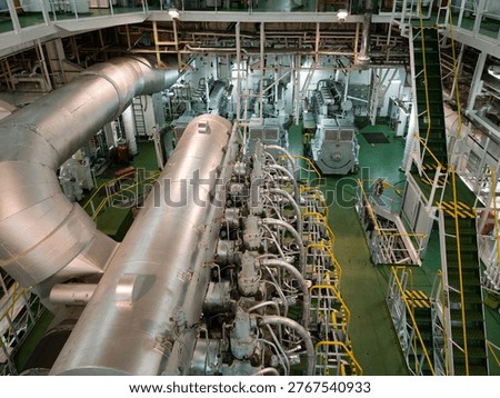 Clean and well-lit ship engine room featuring a large marine engine, structured pipelines, and organized industrial environment.