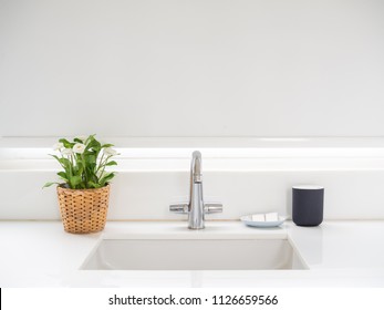 Clean White Bathroom Interior with Sink Basin Faucet, Flower in Weave Pot, Soap and Ceramic Mug. Modern Design of Bathroom with Copy Space.