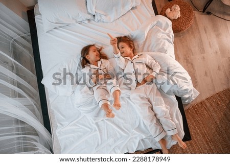 Similar – Mother reading book to her sons in the bed