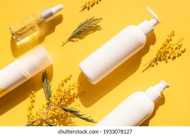 Clean White Cosmetic Containers Bottles With Mimosa Flowers On Yellow Background Flat Lay Top View. Blank Label Package For Branding Mock-up. Spring Cosmetics Concept. Natural Organic Beauty Product